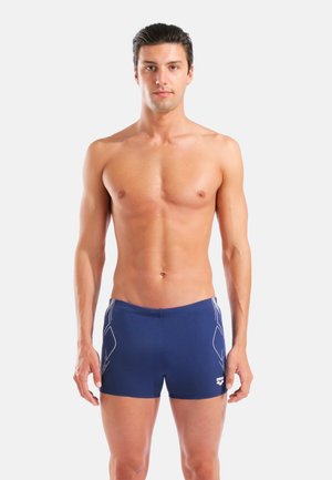 Marineblaue Badeshorts aus Stretchstoff mit weißen Seitenakzenten und figurbetontem Schnitt. Keine sichtbaren Logos oder weiteren Muster.