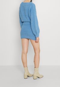 Ljusblå stickad tröja och matchande mini kjol med ett texturerat mönster. Kombinerad med beige ankelstövlar med klack.