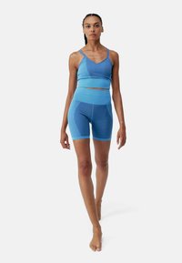 Kék sportmelltartó és magas derekú shorts, texturált szövetből, sima panellel. Vékony pántokkal és testhezálló dizájnnal rendelkezik.