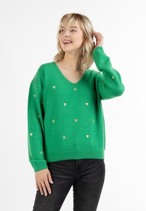 Grøn strikket sweater med v-hals, prydet med guld hjerte mønstre og lange ærmer. Stoffet ser blødt ud med en afslappet pasform.