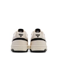 Sneaker beige e nere con colletto imbottito, forma arrotondata e suola in gomma texture. Dettaglio del logo nero sul tallone e sul lato.