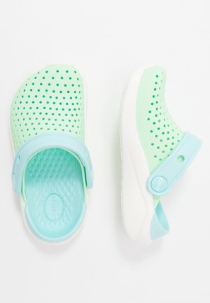 Lysegrønne slip-on-træsko med ventilationshuller, lyseblå justerbare stropper og hvide teksturerede såler vist fra top- og sidevisning.