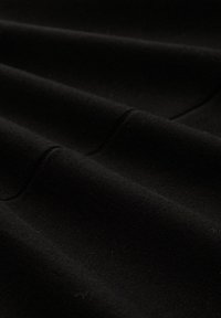 Schwarzer Stoff mit einer weichen, strukturierten Oberfläche in Falten, die ein glattes Finish zeigt. Keine sichtbaren Muster oder Hardwaredetails.