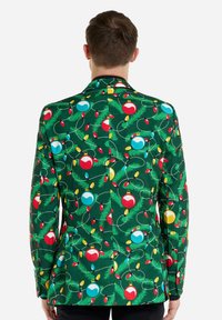 Roheline jakker, millel on pidulik trükk punastest ja sinistest jõulukaunistustest, kollastest ja punastest tuledest ning rohelisest männilehest. Sile tekstuur, istuv disain.
