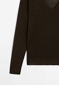 Pull en tricot marron foncé à manches longues avec poignets et ourlet côtelés, col en V, présenté sur fond blanc.