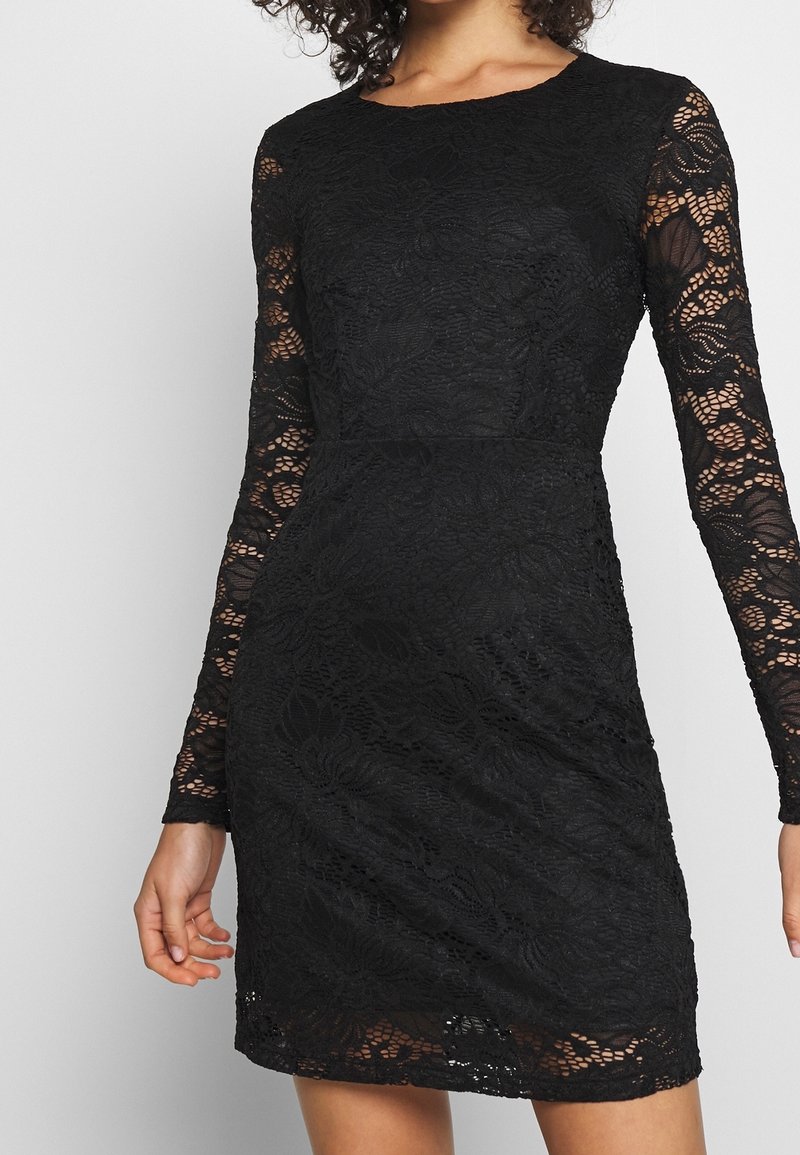 Svart spetsklänning med långa ärmar, skräddarsydd silhuett, blommönster och texturerad yta. Rund halsringning och midjalång längd.