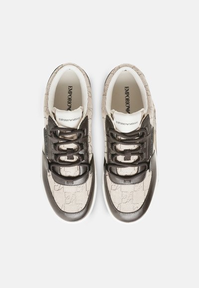 Paire de baskets Emporio Armani beige et noire avec tissu texturé et détails du logo, vues du dessus sur un fond uni.