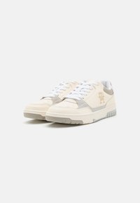 Sneaker color crema realizzate in pelle e camoscio con lacci bianchi, una suola testurizzata e un sottile accento di logo in beige chiaro.