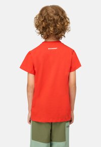 Rotes Baumwoll-T-Shirt mit kurzen Ärmeln, das auf dem Rücken ein weißes "MAMMUT"-Logo zeigt. Das Shirt hat einen klassischen Rundhalsausschnitt und eine glatte Textur.