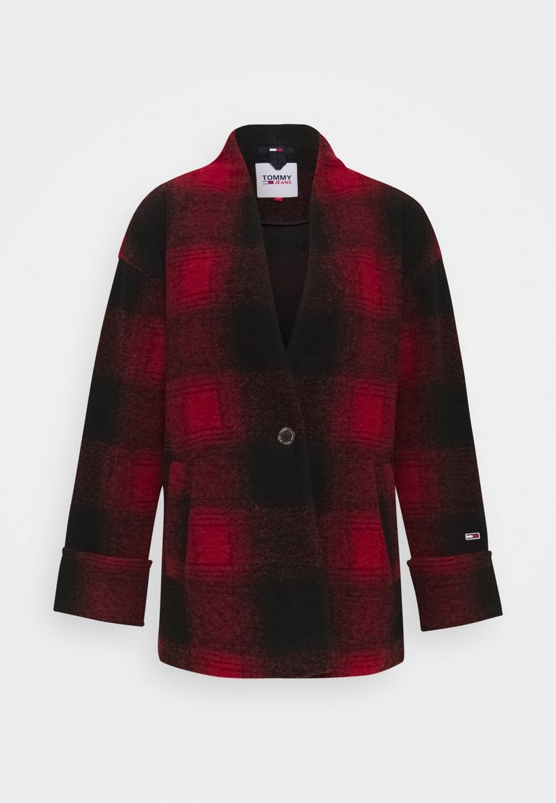 Czerwony i czarny płaszcz w kratę z kołnierzem w stylu szala, zapinany na jeden guzik, z bocznymi kieszeniami. Tkanina wydaje się miękka, o szczotkowanej fakturze.