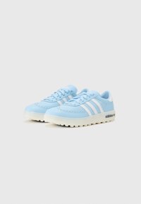 Lyseblå sneakers med hvite striper, laget av syntetisk materiale. Har en teksturert såle og et preget logo på siden.