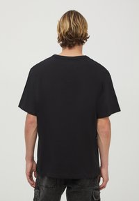 T-shirt nera in cotone con colletto rotondo classico e maniche corte, dal taglio morbido e senza grafiche o decorazioni visibili.