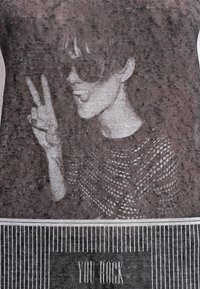 Černobílá pletenina se siluetou osoby v brýlích, která dělá mírové gesto, s textem "TY ROCKUJES" níže.