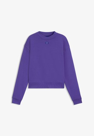 Violetin fleecetakki, jossa on pyöreä kaula-aukko, pitkät hihat ja resorit. Edessä kaula-aukon lähellä pieni sininen logotägi.