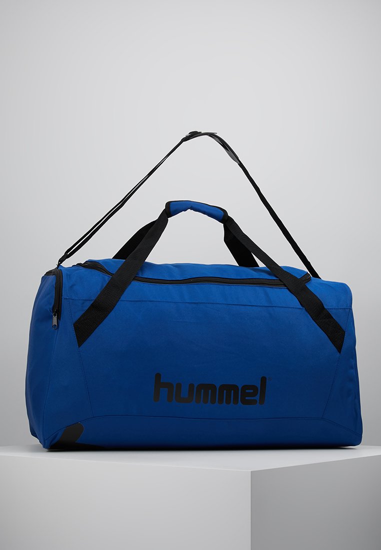 Bolso de viaje azul con correas y cremallera negras, que presenta un gran logotipo. Hecho de tela duradera, tiene una forma rectangular y una textura suave.