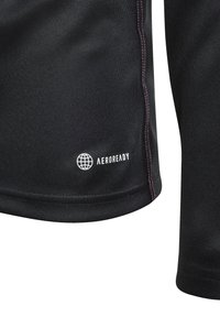 Černá látka s růžovým prošíváním a bílým logem Země doplněným slovem "AEROREADY" na sportovním materiálu.