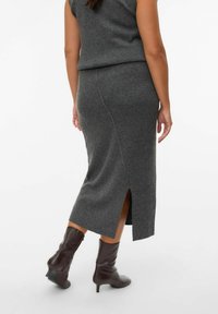Dark gray knitted midi skirt with a side slit, paired with knee-high brown leather boots. Smooth texture, fitted design.