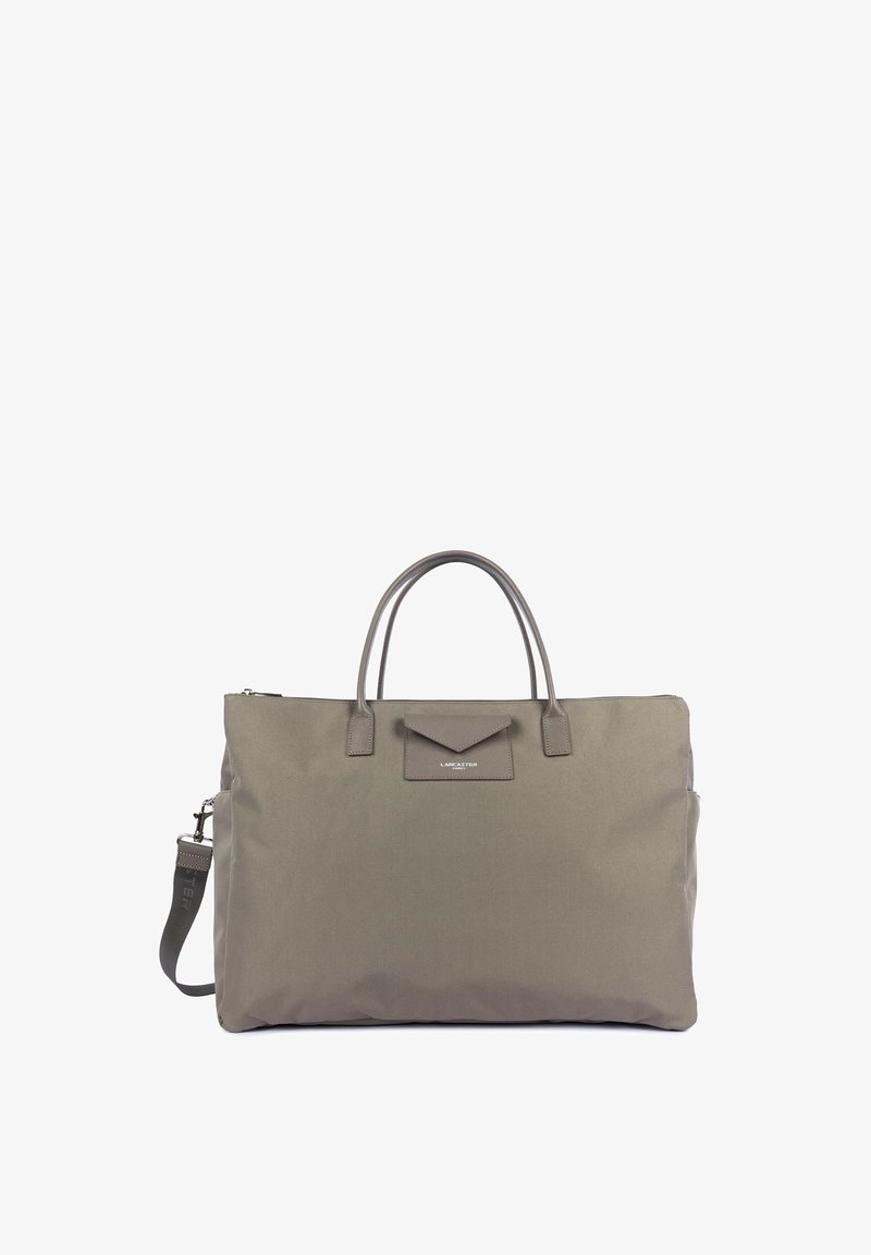 Grand sac cabas taupe avec deux poignées, une bandoulière amovible et une petite poche à rabat étiquetée Lancaster Paris à l’avant.