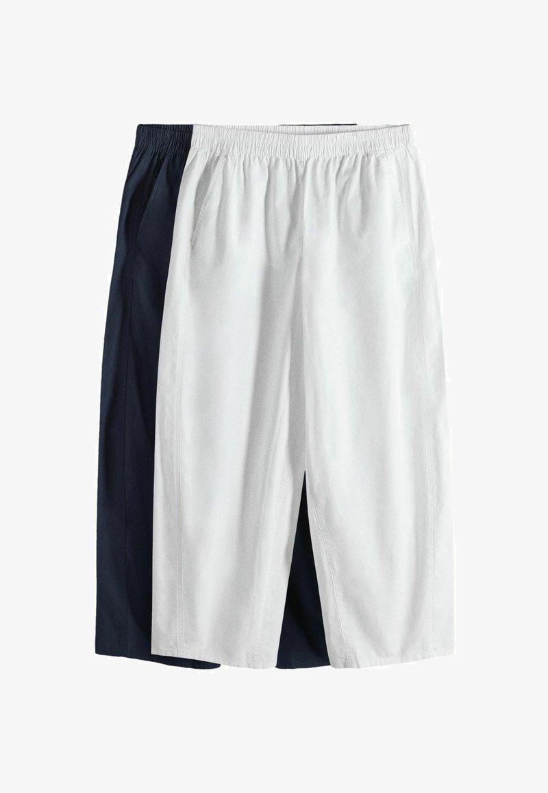 Deux paires de shorts amples avec des ceintures élastiques, un blanc et un bleu marine, superposés sur fond blanc.