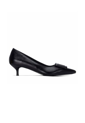 Zapato negro de piel con tacón bajo y puntera puntiaguda, con una hebilla rectangular decorativa en la parte superior, mostrado en perfil lateral sobre fondo blanco.