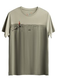 T-shirt in cotone verde oliva con una stampa grafica di una figura in un cappotto rosso che si erge su un paesaggio testurizzato. Maniche corte, collo rotondo.