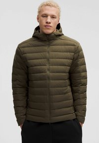 Giubbotto puffo verde con cappuccio, dotato di design trapuntato, chiusura con zip e polsini elasticizzati. Tessuto liscio e leggero.