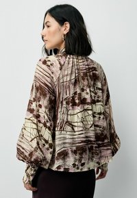 Langdurig mouwblouse in een meerkleurig abstract patroon met bruin- en rozetinten, met geplooide details aan de achterkant en manchetachtige mouwen.