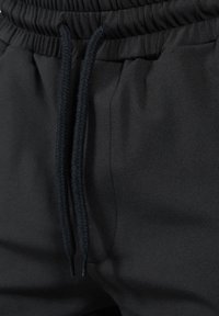 Pantalones de chándal negros con cintura elástica y cordón trenzado. Tela suave con un ligero brillo y sin patrones ni acentos visibles.