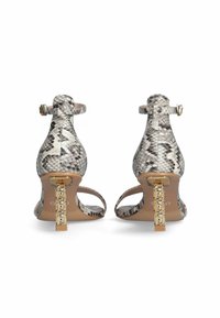 Sandali con tacco alto in stampa serpente, con cinturini alla caviglia regolabili, materiale testurizzato e tacchi a blocco in tonalità oro con accenti decorativi.