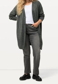 Cardigan de punto gris oscuro con mangas largas y detalles de botones, combinado con jeans grises y zapatos negros tipo slip-on. Textura suave y corte relajado.