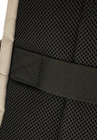 Tessuto in mesh nero con motivo a griglia e una robusta cinghia nera. Lati strutturati con dettagli di cuciture rinforzate. Design leggero.