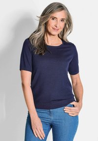 Navyblauwe koker met korte mouwen, een ronde halslijn en geribbelde zoom, gecombineerd met lichtblauwe denim jeans. Soepele textuur en comfortabele pasvorm.