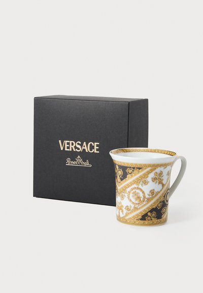 Keramikkrus med sort og hvidt mønster, gulddetaljer og et buet håndtag, præsenteret ved siden af en sort æske mærket "Versace Rosenthal."