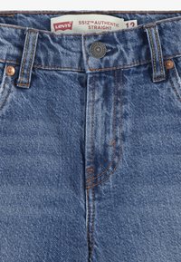 Levi's 551Z Authentic Straight jeans, tillverkade av blå denim med kopparstygn, med knappstängning och klassisk femfickorsdesign.