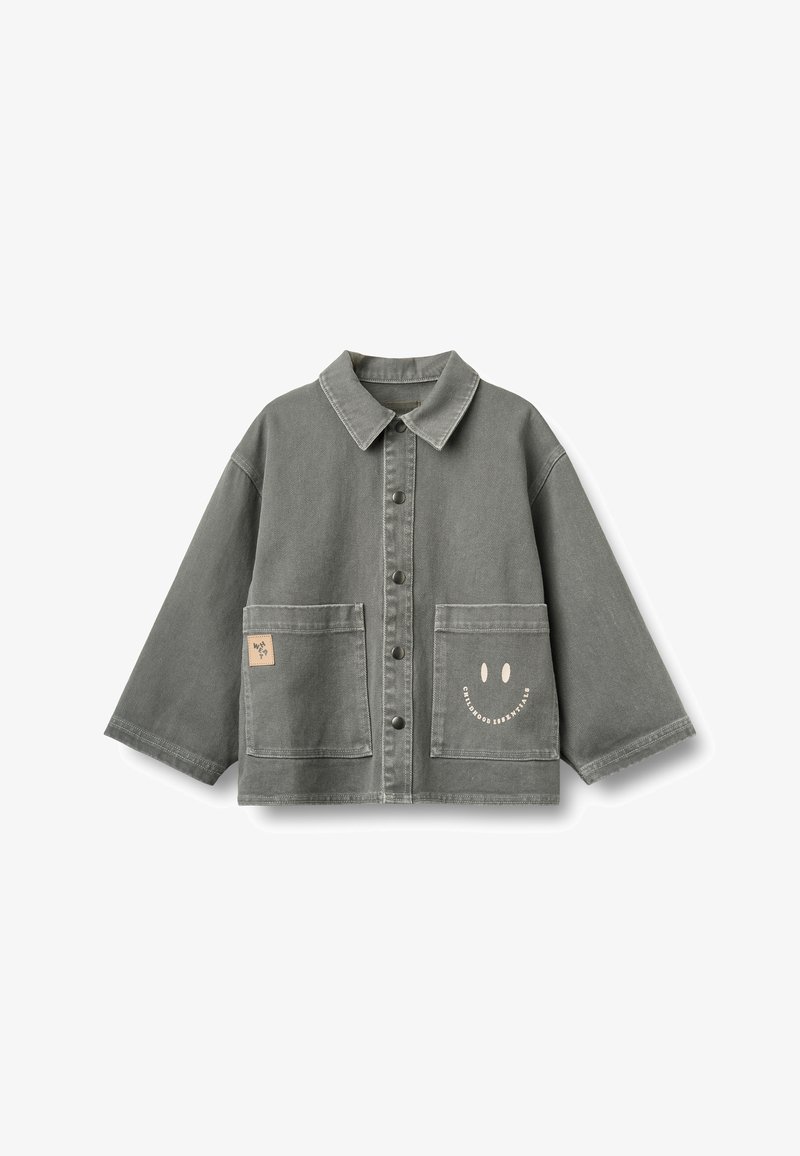 Veste gris boutonnée avec manches larges, deux poches avant, un petit écusson sur la poche gauche et un visage souriant avec texte sur la poche droite.