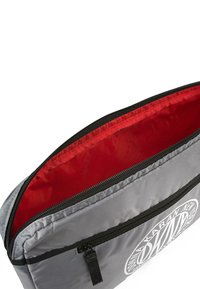 Bolsa de tela gris con cierre de cremallera, con forro interior rojo y estampado de logotipo blanco en un lado. Exterior texturizado con acabado suave.