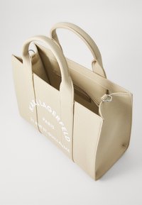 Sac fourre-tout en cuir beige avec deux courtes poignées, finition texturée, poches latérales et logo imprimé en blanc à l'avant. Compartiment intérieur avec fermeture éclair.