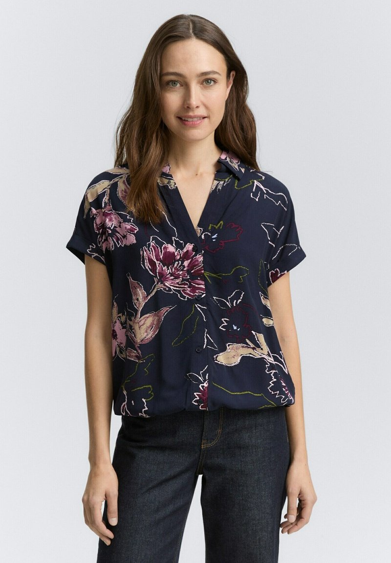 Blusa floreale navy con maniche corte, caratterizzata da motivi di fiori rosa e verdi e una chiusura con bottoni davanti. Tessuto leggero e morbido.