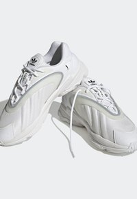 Vita sportiga sneakers i mesh och syntetmaterial, med vadderad krage, texturerade paneler och en gummisula med accentdetaljer.