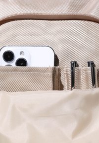 Borsa beige chiaro con texture, con una sezione che contiene uno smartphone bianco e due penne metalliche, caratterizzata da una fodera in tessuto liscio.