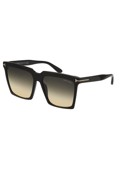 Gafas de sol negras cuadradas con un marco grueso y lentes degradados, que presentan un acabado en dorado y un diseño moderno. Logo de la marca visible en la patilla.