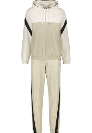 Lichtbeige trainingspak van zijdeachtige stof, met een capuchonjack met een witte bovenpaneel en zwarte zijstrepen, gecombineerd met tapered broek.