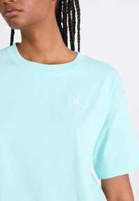 Lyseblå bomulds t-shirt med rund hals og korte ærmer, der har et lille hvidt broderet Jumpman-logo på venstre bryst.