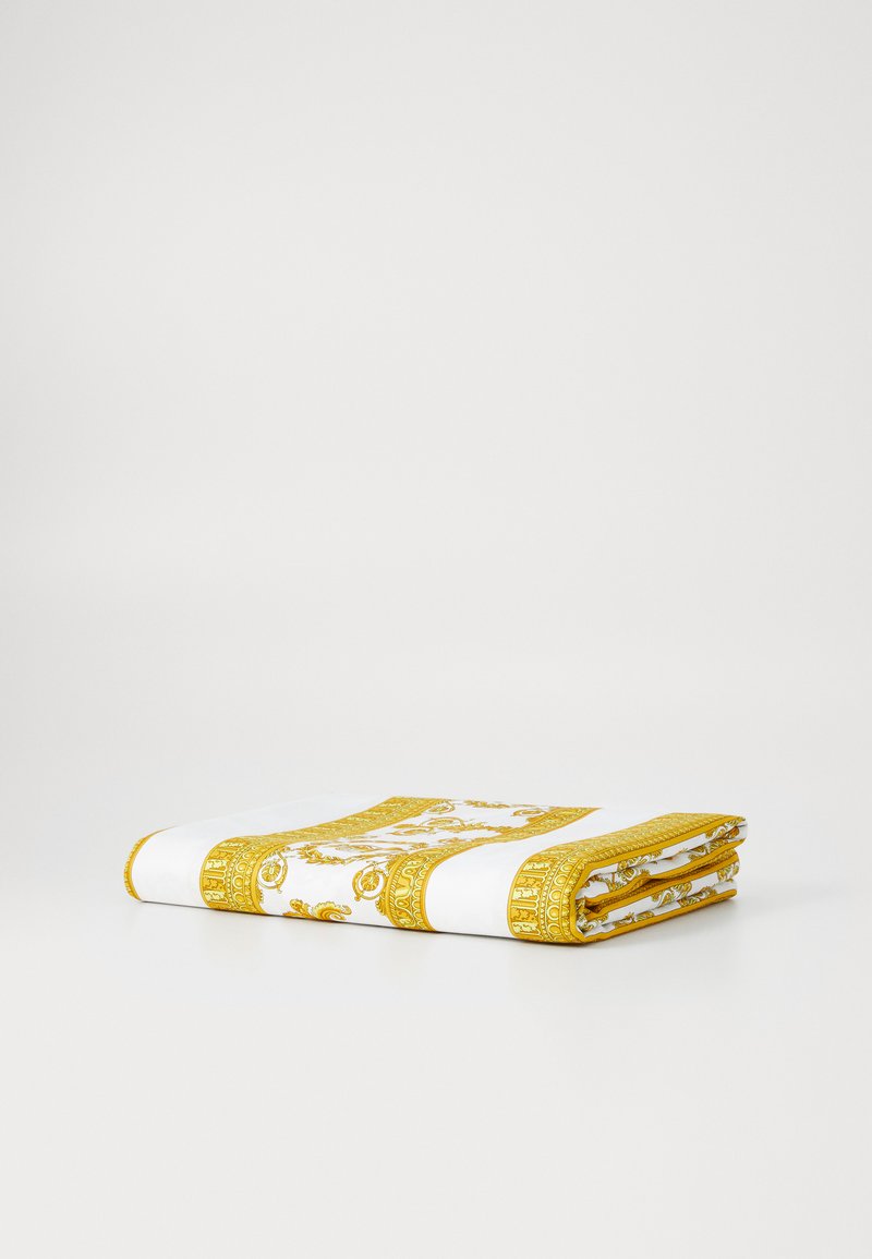 Folded blanket in white with intricate gold patterns and borders. Features a smooth texture and vibrant yellow trim.
