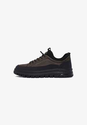 Sneakers in grigio scuro e nero, con una parte superiore liscia caratterizzata da texture in suede e mesh, lacci rotondi e una suola imbottita con un battistrada decorato.