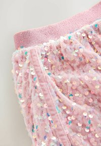 Rosa Paillettenstoff mit einer strukturierten Oberfläche, elastischem Bund und glänzenden, eng angeordneten runden Pailletten, die visuelles Interesse hinzufügen.