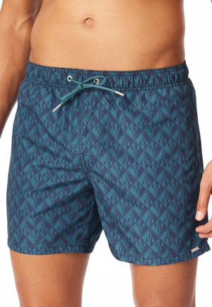 Mann trägt türkisfarbene Badeshorts mit dunkelblauem Hummermuster und einem elastischen Bund mit gebundener Kordel.