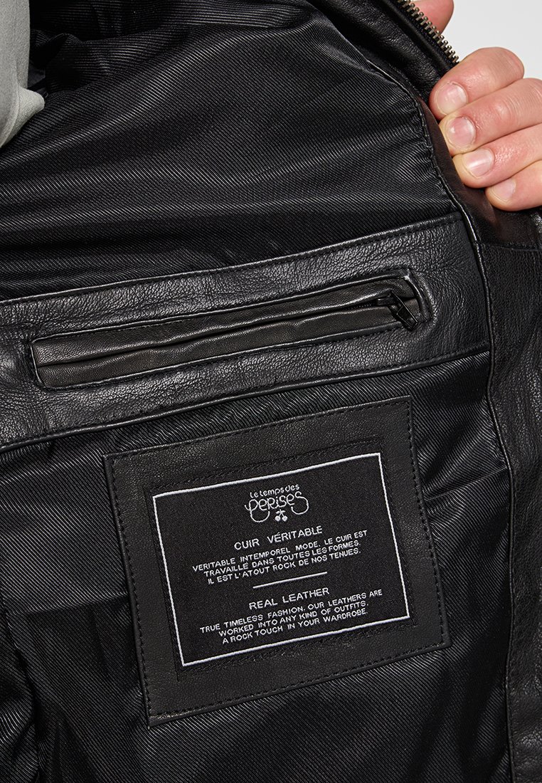 Interno di una giacca di pelle nera con una finitura liscia, dotato di una tasca con zip, rivestimento in tessuto e un'etichetta che indica "pelle vera".