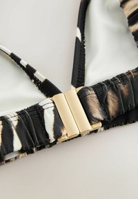 Zwart-wit gestreepte bikini-top van glad, rekbaar materiaal. Voorzien van een metallic gouden sluiting in het midden. Getextureerde randen.
