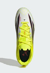 Λευκό και φωτεινό κίτρινο παπούτσι ποδοσφαίρου με μαύρες λεπτομέρειες. Διαθέτει υφή στην επάνω επιφάνεια, ανυψωμένα μοτίβα και εμφανές λογότυπο στην εσωτερική σόλα.